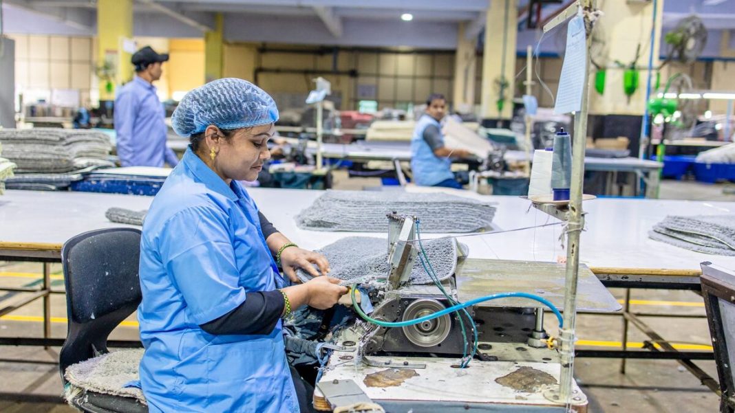 A female worker in a factory setting using a sewing machine for textile production.